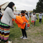 
              Students at Red Cloud Indian School wait in line to receive orange T-shirts after an assembly Sept. 30, 2021, in Pine Ridge, S.D. Students and teachers wore orange in solidarity with Indigenous children of past generations who suffered cultural loss, family separation and sometimes abuse and neglect while compelled to attend hundreds of residential schools that once dotted the map across the United States and Canada from the late 19th to the mid-20th centuries. (AP Photo/Emily Leshner)
            