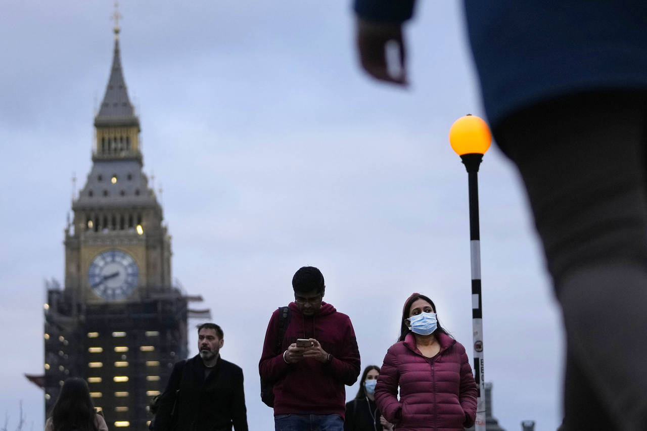 People partly wearing a face covering walk across Westminster Bridge in London, Wednesday, Dec. 15,...