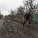 
              Halyna Moroka tries to cross a bumpy road near her house in the village of Nevelske in eastern Ukraine, Friday, Dec. 10, 2021. The 7-year-old conflict between Russia-backed separatists and Ukrainian forces has all but emptied the village. “We have grown accustomed to the shelling,” said Moroka, 84, who has stayed in Nevelske with her disabled son. (AP Photo/Andriy Dubchak)
            