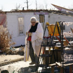 
              Martha Thomas stays warm with a bed comforter as volunteers help her salvage possessions from her destroyed home in the aftermath of tornadoes that tore through the region, in Mayfield, Ky., Monday, Dec. 13, 2021. (AP Photo/Gerald Herbert)
            