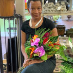 
              In this May 31, 2019, photo provided by Angie Morton, Lisa Taylor poses with a flower arrangement taken at Rachel’s Flowers in Memphis, Tenn. An emergency management official in Shelby County, Tenn., said Taylor was found dead Saturday, Dec. 11, 2021, after a tree uprooted in a violent storm fell through the roof of her Memphis home, landing on Taylor as she slept. Co-workers said she recently left her job as a florist of 14 years for a government job at the Memphis airport. (Angie Morton via AP)
            