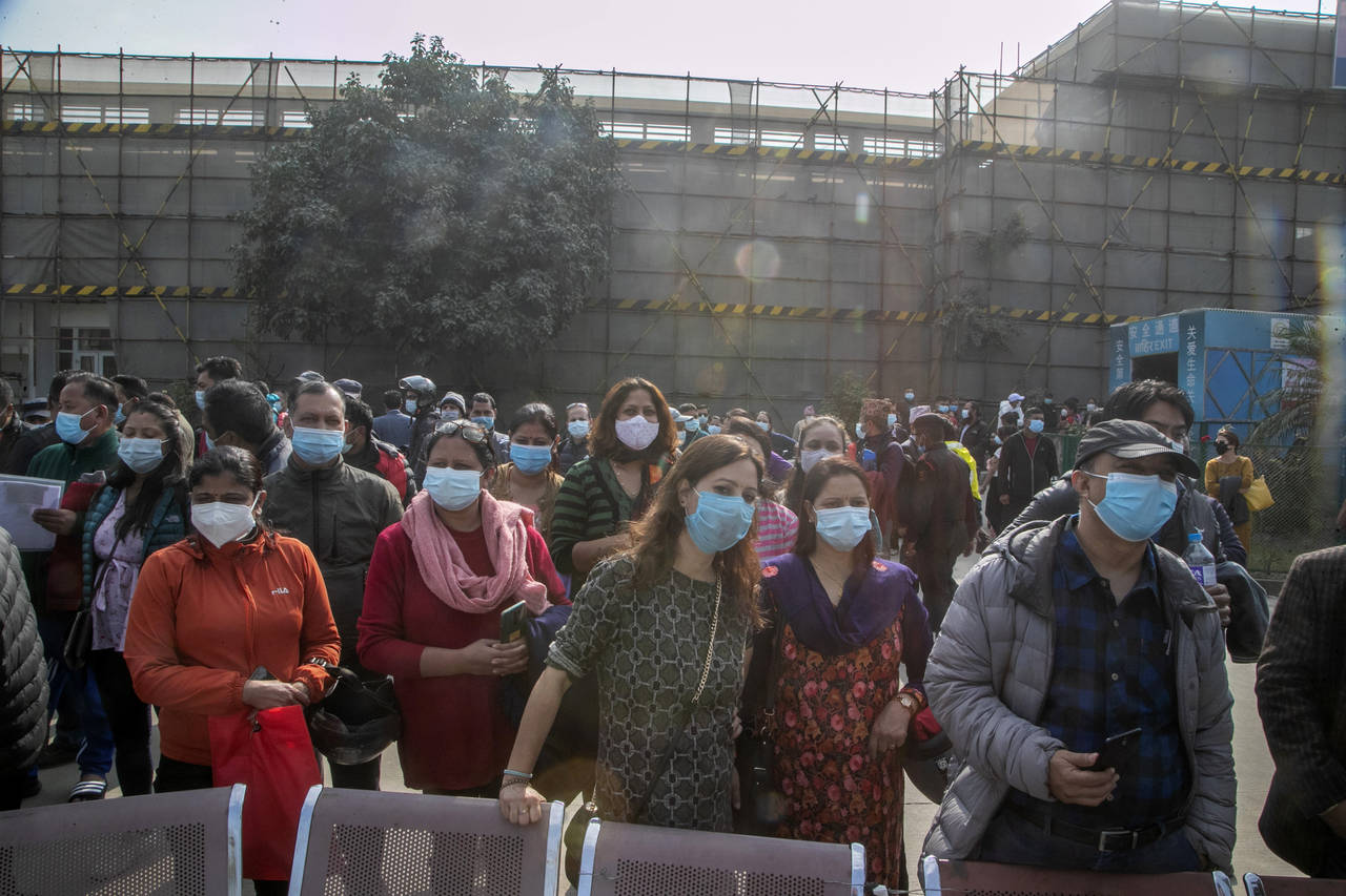 FILE- Adults wait for children receiving the Pfizer-BioNTech vaccine for COVID-19 in Kathmandu, Nep...