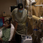 
              Respiratory therapist Frans Oudenaar adjusts the oxygen flow rate for Linda Calderon, 71, in a COVID-19 unit at Providence Holy Cross Medical Center in Los Angeles, Tuesday, Dec. 14, 2021. (AP Photo/Jae C. Hong)
            