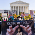 
              FILE - Stephen Parlato of Boulder, Colo., holds a sign that reads "Hands Off Roe!!!" as abortion rights advocates and anti-abortion protesters demonstrate in front of the U.S. Supreme Court, Dec. 1, 2021, in Washington, as the court hears arguments in a case from Mississippi, where a 2018 law would ban abortions after 15 weeks of pregnancy, well before viability. As 2021 comes to a close, Roe v. Wade — the historic 1973 Supreme Court ruling establishing a nationwide right to abortion — is imperiled as never before. (AP Photo/Andrew Harnik, File)
            