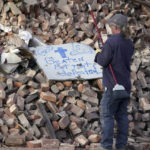
              Rick Vincent, of Newaygo, Mich., reads a sign placed on a pile of building rubble as he stops work at the end of the day, Sunday, Dec. 12, 2021, in Mayfield, Ky. Vincent, a retired teacher, has come to Mayfield on his own to volunteer to help in the cleanup effort after tornadoes and severe weather caused catastrophic damage across several states Friday, killing multiple people. (AP Photo/Mark Humphrey)
            