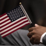 
              FILE - Leon Small, originally from Jamaica, holds a United States flag in a naturalization ceremony, Wednesday, April 28, 2021, in New York. While on the brink of furloughing 70% of its roughly 20,000 employees that summer, U.S. Citizenship and Immigration said almost overnight that it would end the year with the large surplus. (AP Photo/Mark Lennihan, File)
            