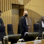
              Presiding judge Hendrik Steenhuis, center, looks into the public gallery as he arrives in the courtroom for the ongoing trial and criminal proceedings regarding the downing of Malaysia Airlines flight MH17, at the high security court at Schiphol airport, near Amsterdam, Netherlands, Monday Dec. 20, 2021. Prosecutors are scheduled to begin explaining evidence and their case to judges Monday in the murder trial of three Russians and a Ukrainian charged with involvement in downing Malaysia Airlines flight MH17 over eastern Ukraine in 2014, killing all 298 passengers and crew. (AP Photo/Peter Dejong)
            