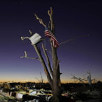 
              An American flag hangs from a damaged tree Sunday, Dec. 12, 2021, in Mayfield, Ky. Tornadoes and severe weather caused catastrophic damage across several states Friday, killing multiple people. (AP Photo/Mark Humphrey)
            