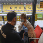 
              Onays Al-Sadi , left, team doctor of soccer club SG Dynamo Dresden, inoculates awoman with Moderna's vaccine against the coronavirus in a VIP lounge during a vaccination campaign at the Rudolf Harbig Stadium, the home ground of the second division football team in Dresden, Germany, Tuesday, Dec. 14, 2021.(Robert Michael/dpa via AP)
            