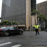
              A police officer directs traffic during a power outage in downtown Honolulu after a severe winter storm swept the islands, Tuesday, Dec. 7, 2021. (AP Photo/Caleb Jones)
            