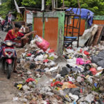 
              A man throws adds a bag of waste to an open garbage dump in Jakarta, Indonesia, Tuesday, Jan. 25, 2022. Indonesian parliament last week passed the state capital bill into law, giving green light to President Joko Widodo to start a $34 billion construction project this year to move the country's capital from the traffic-clogged, polluted and rapidly sinking Jakarta on the main island of Java to jungle-clad Borneo island amid public skepticism. (AP Photo/Dita Alangkara)
            