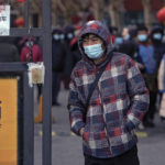 
              A man wearing a face mask to help protect from the coronavirus walks by residents gathered for a line for a throat swab at a COVID-19 test site outside a residential housing block in Fengtai District in Beijing, Wednesday, Jan. 26, 2022. The Chinese capital reported an uptick more than dozen daily new COVID-19 cases as it began a third round of mass testing of millions of people Wednesday in the run-up to the Winter Olympics. (AP Photo/Andy Wong)
            