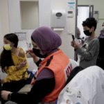 
              N'amah Yetzhak Abohaikal, a volunteer with the women's unit of United Hatzalah emergency service, prepares administer the COVID-19 vaccine to a teen girl as her brother and grandmother watch, at Clalit Health Services in Mevaseret Zion, Tuesday, Jan. 11, 2022. (AP Photo/Maya Alleruzzo)
            