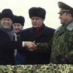 
              FILE - Secretary of Defense William Perry, left, shakes hands with Ukraine Defense Minister Valery Shmarov, center, and Russian Defense Minister Pavel Grachev as they stand over the crater which formerly housed a missile silo at a military base near Pervomaysk, some 155 miles south of Kyiv, on Jan. 5, 1996. With the turn of a key the U.S., Russia and Ukraine defense chiefs put an end to the missile silo Friday that once held nuclear weapons aimed at the United States. (AP Photo/Efrem Lukatsky, File)
            