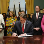 
              Virginia Gov. Glenn Youngkin, center, signs executive orders in the Governors conference room as Lt. Gov. Winsome Earle-Sears, left, Suzanne Youngkin, Second from left, Attorney General Jason Miyares, second from right, and Secretary of the Commonwealth, Kay Cole James, right, look on at the Capitol Saturday Jan. 15, 2022, in Richmond, Va. (AP Photo/Steve Helber)
            