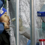 
              In this photo released by Xinhua News Agency, a child gets a throat swab for the COVID-19 test at a residential area in Fengtai District in Beijing, Sunday, Jan. 23, 2022. People in a Beijing district with some 2 million residents were ordered Sunday to undergo mass coronavirus testing following a series of infections as China tightened anti-disease controls ahead of the Winter Olympics. (Tang Rufeng/Xinhua via AP)
            