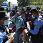 
              Honduran police check documents of migrants who are part of a caravan hoping to reach the United States, in Corinto, Honduras, Saturday, Jan. 15, 2022. (AP Photo/Delmer Martinez)
            