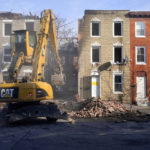 
              An excavator is used to pull debris off a building during efforts to retrieve the body of a deceased firefighter caught in the building's collapse while battling a two-alarm fire in the vacant row home, Monday, Jan. 24, 2022, in Baltimore. Officials said several firefighters died during the blaze. (AP Photo/Julio Cortez)
            