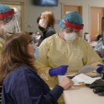 
              Registered nurses Sarah Carr, top left, and Lindsay Holloran, right, are suited up with protective gear before entering a patient's room at the COVID-19 Intensive Care Unit at Dartmouth-Hitchcock Medical Center, in Lebanon, N.H., Monday, Jan. 3, 2022. Doctors and nurses, once lauded for their service, complain about burnout and a sense their neighbors are no longer treating the pandemic as a health emergency — despite day after day of record COVID-19 cases in the state. (AP Photo/Steven Senne)
            