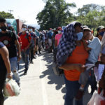 
              Migrants who are part of a caravan hoping to reach the United States, wait in a line as they wait to have their documents checked by police in Corinto, Honduras, Saturday, Jan. 15, 2022. (AP Photo/Delmer Martinez)
            