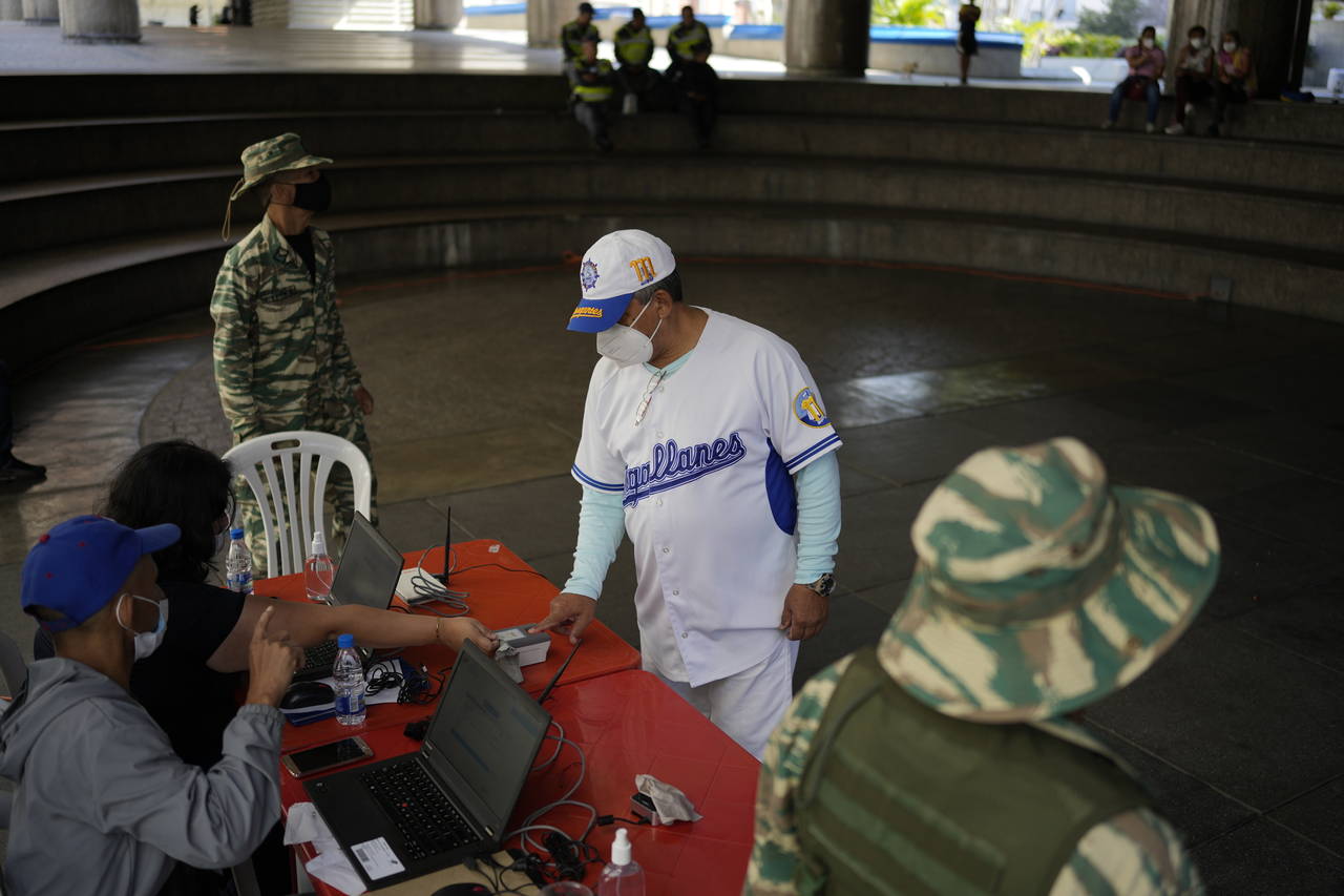 A man gives his fingerprint at a table set up by the National Election Council (CNE) where people c...