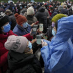 
              Volunteers help women enter information on their smartphones as others gather in line for mass coronavirus testing in Beijing, Monday, Jan. 24, 2022. Chinese authorities have lifted a monthlong lockdown of Xi'an and its 13 million residents as infections subside ahead of the Winter Olympics. Meanwhile, the 2 million residents of one Beijing district are being tested following a series of cases in the capital. (AP Photo/Andy Wong)
            