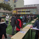 
              Volunteers wearing face masks to help protect from the coronavirus check name lists at a coronavirus testing facility at a school in Fengtai District in Beijing, Monday, Jan. 24, 2022. Chinese authorities have lifted a monthlong lockdown of Xi'an and its 13 million residents as infections subside ahead of the Winter Olympics. Meanwhile, the 2 million residents of one Beijing district are being tested following a series of cases in the capital. (AP Photo/Andy Wong)
            