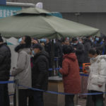 People wearing face masks to help protect from the coronavirus line up to get a swab for the COVID-19 test at a hospital in Beijing, Sunday, Jan. 23, 2022. Chinese authorities have called on the public to stay where they are during the Lunar New Year instead of traveling to their hometowns for the year's most important family holiday. (AP Photo/Andy Wong)