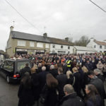 
              Ashling Murphy's family and mourners walk behind the hearse as it leaves St. Brigid's Church, Mountbolus, Co Offaly, Ireland, Tuesday, Jan. 18, 2022 at the end of the funeral of the school teacher who was murdered in Tullamore, Co Offaly last Wednesday.  Hundreds of mourners in Ireland turned out Tuesday for the funeral mass of a 23-year-old schoolteacher whose murder has reignited debate about how to tackle violence against women. The body of Ashling Murphy, a musician and teacher, was found on the banks of a canal in Tullamore in central Ireland on Jan.12. (Niall Carson/PA via AP)
            