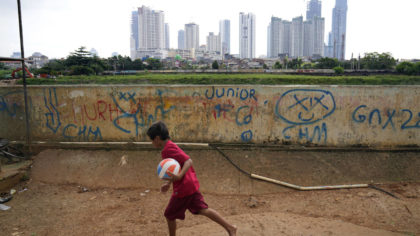 A young boy plays as high rise buildings at the main business district are seen in the background, ...