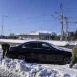 
              Greek soldiers try to free a vehicle stuck in snow on the Attiki Odos motorway, following Tuesday's heavy snowfall, in Athens, on Wednesday, Jan. 26, 2022. (AP Photo/Thanassis Stavrakis)
            