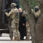 
              Shortly after 5 p.m., local time, authorities escort a hostage out of the Congregation Beth Israel synagogue in Colleyville, Texas, Saturday, Jan. 15, 2022. Police said the man was not hurt and would be reunited with his family. (Elias Valverde/The Dallas Morning News via AP)
            