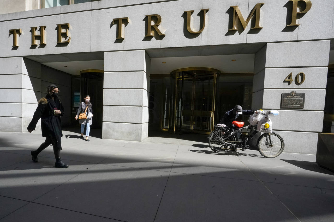FILE - Pedestrians and a food delivery man are seen outside the Trump building at 40 Wall Street in...