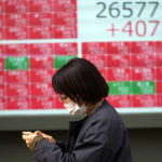 
              A woman wearing a protective mask walks in front of an electronic stock board showing Japan's Nikkei 225 index at a securities firm Friday, Jan. 28, 2022, in Tokyo. Asian stock markets were mixed Friday as traders looked ahead to data on U.S. employment costs that might influence Federal Reserve decisions on planned interest rate hikes. (AP Photo/Eugene Hoshiko)
            