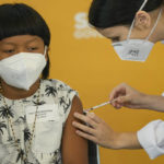 
              A health worker gives a shot of the Pfizer COVID-19 vaccine to 8-year-old Indigenous youth Davi Seremramiwe Xavante at the Hospital da Clinicas in Sao Paulo, Brazil, Friday, Jan. 14, 2022. The state of Sao Paulo started the COVID-19 vaccination of children between ages 5 and 11. (AP Photo/Andre Penner)
            