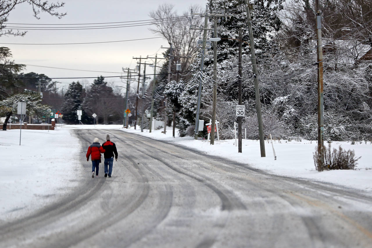 People walk through the snow along West County Street in Hampton, Va., Saturday, Jan. 22, 2022. A l...