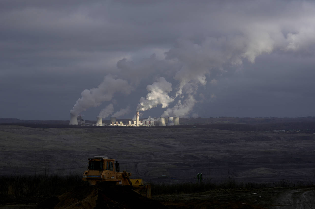 Smoke rises from chimneys of Turow power plant located by the Turow lignite coal mine near the town...