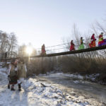 
              Participants, dressed in traditional costumes, cross a bridge while celebrating the Malanka festival in the village of Krasnoilsk, Ukraine, Friday, Jan. 14, 2022. Dressed as goats, bears, oxen and cranes, many Ukrainians rang in the new year last week in the colorful rituals of the Malanka holiday. Malanka, which draws on pagan folk tales, marks the new year according to the Julian calendar, meaning it falls on Jan. 13-14. In the festivities, celebrants go from house to house, where the dwellers offer them food. (AP Photo/Ethan Swope)
            