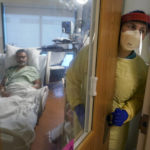 
              Registered nurse Rachel Chamberlin, of Cornish, N.H., right, steps out of an isolation room where where Fred Rutherford, of Claremont, N.H., left, recovers from COVID-19 at Dartmouth-Hitchcock Medical Center, in Lebanon, N.H., Monday, Jan. 3, 2022. Hospitals like this medical center, the largest in New Hampshire, are overflowing with severely ill, unvaccinated COVID-19 patients from northern New England. If he returns home, Rutherford said, he promises to get vaccinated and tell others to do so, too. (AP Photo/Steven Senne)
            