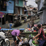 
              Men put garbage bags into an open dumpster in a low-income neighborhood in Jakarta, Indonesia, Tuesday, Jan. 25, 2022. Indonesian parliament last week passed the state capital bill into law, giving green light to President Joko Widodo to start a $34 billion construction project this year to move the country's capital from the traffic-clogged, polluted and rapidly sinking Jakarta on the main island of Java to jungle-clad Borneo island amid public skepticism. (AP Photo/Dita Alangkara)
            