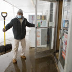
              A man who identified himself at Hollywood 4ever shovels the sidewalk and opens the door for other customers during the snow storm at Food Way Market Sunday, Jan. 16, 2022, in Roanoke.(Scott P. Yates/The Roanoke Times via AP)
            