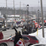 
              Protesters and supporters against a COVID-19 vaccine mandate for cross-border truckers cheer as a parade of trucks and vehicles pass through Kakabeka Falls outside of Thunder Bay, Ontario, on Wednesday, Jan. 26, 2022. (David Jackson/The Canadian Press via AP)
            