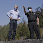 FILE - Washington Gov. Jay Inslee, left, talks with East Pierce Fire and Rescue Chief Bud Backer, right, Sept. 9, 2020, during a tour to survey wildfire damage in Bonney Lake, Wash., south of Seattle. Democratic governors such as California's Gavin Newsom and Washington's Inslee have been clear about their plans to boost spending on climate-related projects, including expanding access to electric vehicles and creating more storage for clean energies such as solar. (AP Photo/Ted S. Warren, Pool, File)