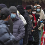 
              A volunteer wearing a face mask to help protect from the coronavirus checks the name list as residents line up during a mass coronavirus testing at a school in Fengtai District in Beijing, Monday, Jan. 24, 2022. Chinese authorities have lifted a monthlong lockdown of Xi'an and its 13 million residents as infections subside ahead of the Winter Olympics. Meanwhile, the 2 million residents of one Beijing district are being tested following a series of cases in the capital. (AP Photo/Andy Wong)
            