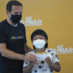 
              Eight-year-old Indigenous youth Davi Seremramiwe Xavante shows his COVID-19 vaccination card, alongside the Governor of Sao Paulo Joao Doria, after getting a shot of the Pfizer vaccine during a vaccination campaign for children at the Hospital da Clinicas in Sao Paulo, Brazil, Friday, Jan. 14, 2022. The state of Sao Paulo started the COVID-19 vaccination of children between ages 5 and 11. (AP Photo/Andre Penner)
            