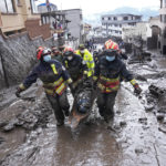 
              Rescue workers carry away the body of a victim after flash flooding triggered by rain filled up nearby streams that burst their containment mechanisms, collapsing a hillside and bringing waves of mud over homes in La Gasca area of Quito, Ecuador, Tuesday, Feb. 1, 2022. (AP Photo/Dolores Ochoa)
            