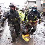 
              Rescue workers carry away the body of a victim of flash flooding triggered by rain filling up nearby streams that burst their containment mechanisms, collapsing a hillside and bringing waves of mud over homes in La Gasca area of Quito, Ecuador, Tuesday, Feb. 1, 2022. (AP Photo/Dolores Ochoa)
            