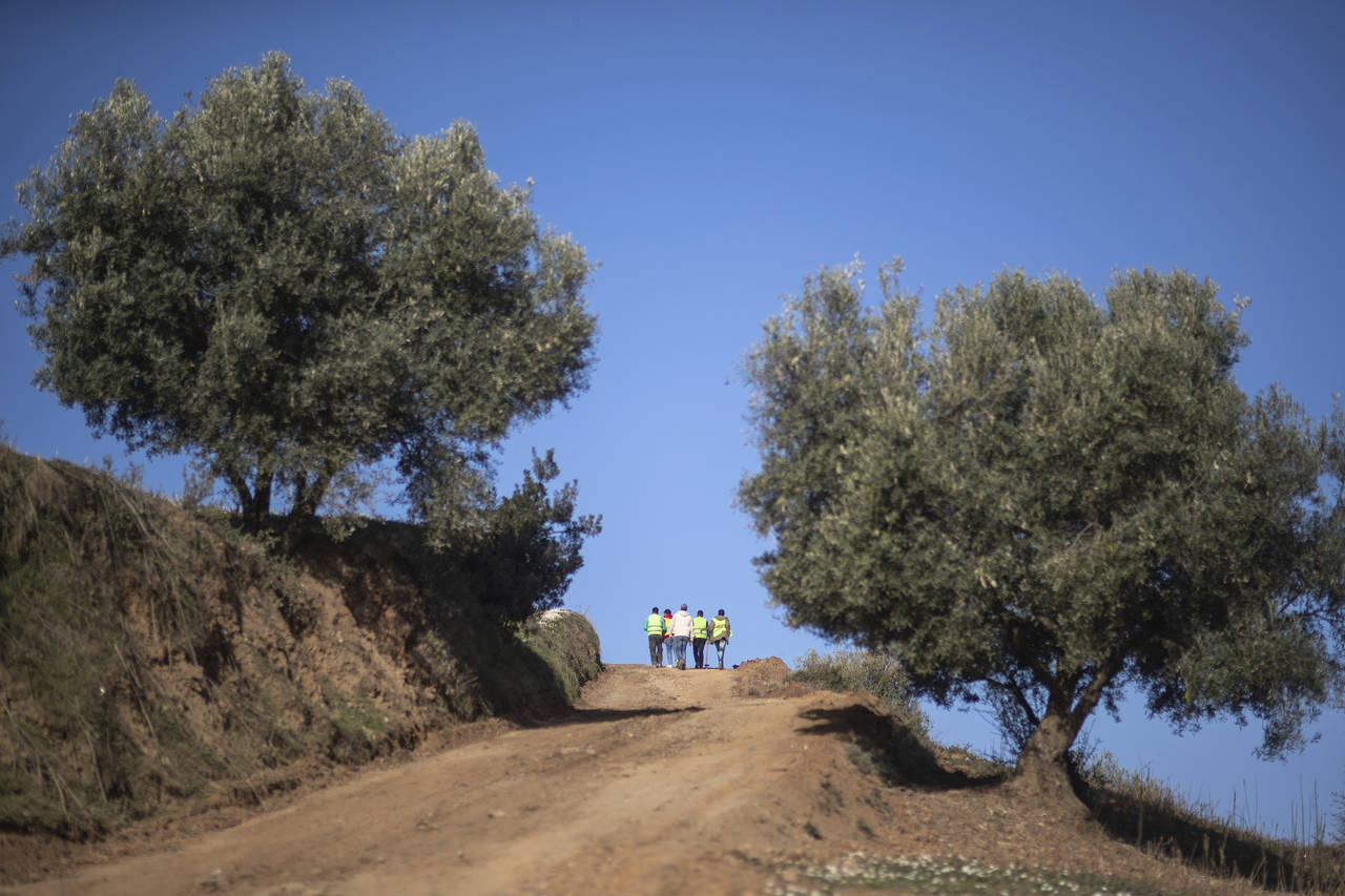 Workers climb a hill to prepare the funeral of 5-year-old Rayan after his body was retrieved from a...