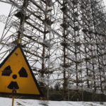 
              FILE - A Soviet-era top secret object Duga, an over-the-horizon radar system once used as part of the Soviet missile defense early-warning radar network, seen behind a radioactivity sign in Chernobyl, Ukraine, on Nov. 22, 2018. Among the most worrying developments on an already shocking day, as Russia invaded Ukraine on Thursday, was warfare at the Chernobyl nuclear plant, where radioactivity is still leaking from history's worst nuclear disaster 36 years ago. (AP Photo/Efrem Lukatsky, File)
            
