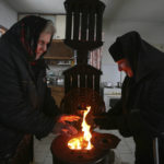 
              FILE - A nun and visitor try to stay warm near a wood-burning stove in a monastery near the Bulgarian capital Sofia, Friday, Jan. 9, 2009. Fears are rising about what would happen to Europe’s energy supply if Russia were to invade Ukraine and then shut off its natural gas in retaliation for U.S. and European sanctions. (AP Photo/Petar Petrov, File)
            